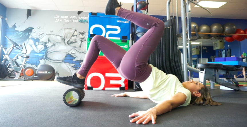 Personal trainer doing glute exercise on a foam roller